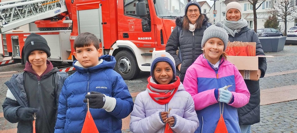 Kinder und Lehrerinnen mit Weihnachtsbaumanhänger vor Feuerwehrauto